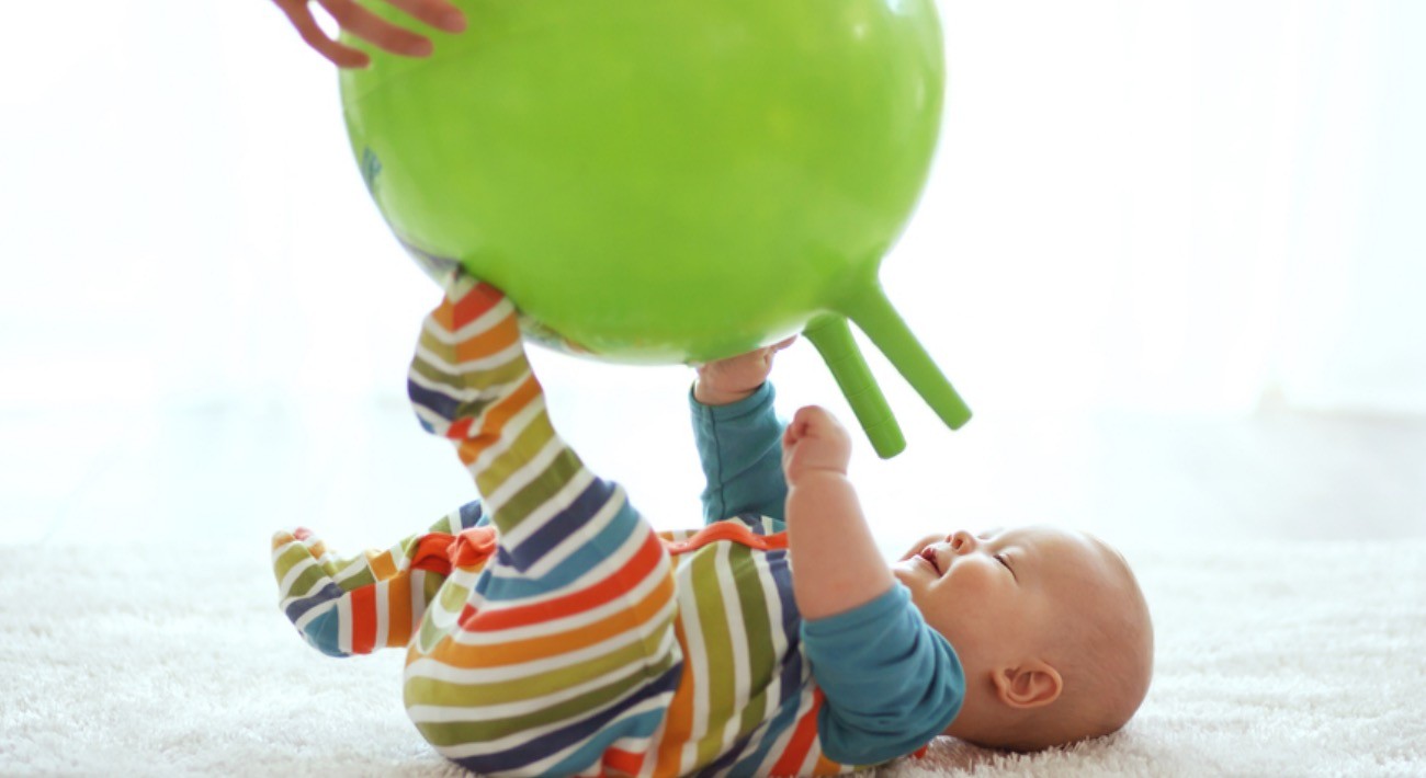 Ovoj bebi se jako dopao oblik i boja lopte. Pokušava da je uhvati obema rukama.